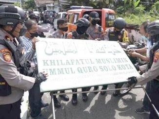 Polisi menurunkan papan bertuliskan Khilafatul Muslimin dari kantor cabang kelompok tersebut di Solo, Jawa Tengah. (AntaraFoto)
